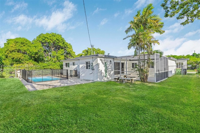 back of property with a patio area, a fenced in pool, a lawn, and glass enclosure