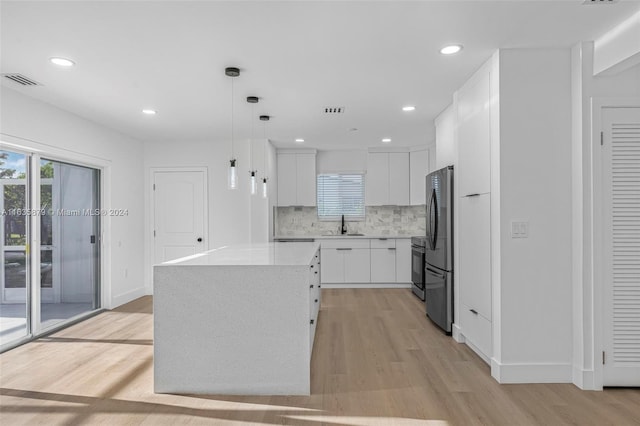 kitchen featuring a center island, pendant lighting, white cabinetry, light wood-type flooring, and appliances with stainless steel finishes