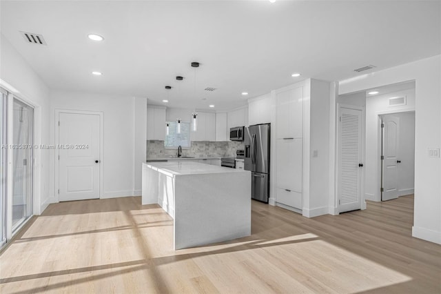 kitchen featuring appliances with stainless steel finishes, a center island, pendant lighting, and white cabinets