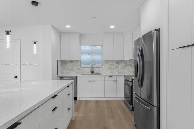 kitchen featuring appliances with stainless steel finishes, light hardwood / wood-style flooring, pendant lighting, and white cabinets