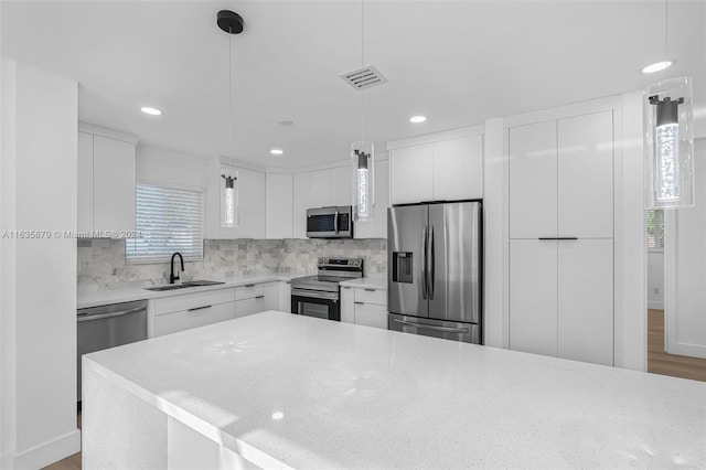 kitchen featuring white cabinetry, stainless steel appliances, light hardwood / wood-style flooring, and hanging light fixtures