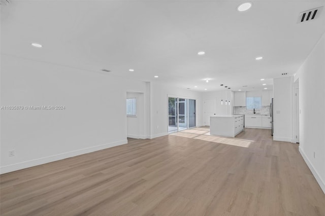 unfurnished living room featuring sink and light hardwood / wood-style flooring