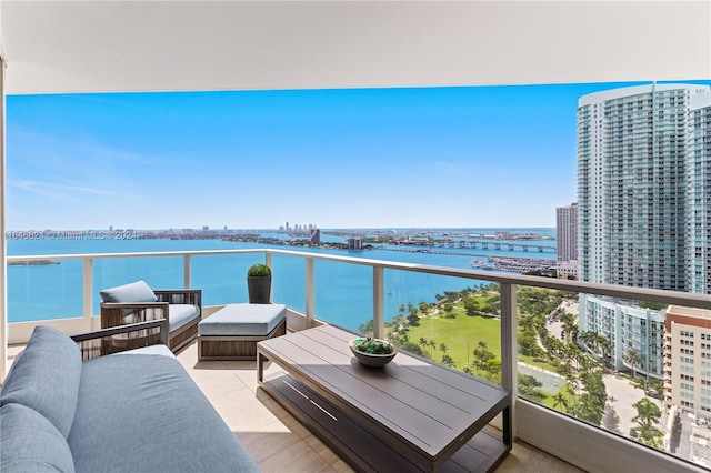 balcony with an outdoor living space and a water view