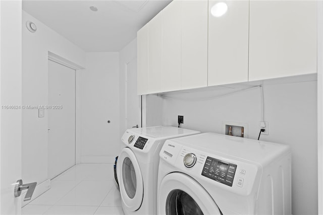 clothes washing area featuring cabinets, light tile patterned floors, and washing machine and clothes dryer