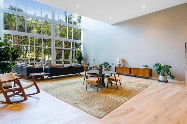 dining area with a high ceiling, expansive windows, and wood-type flooring