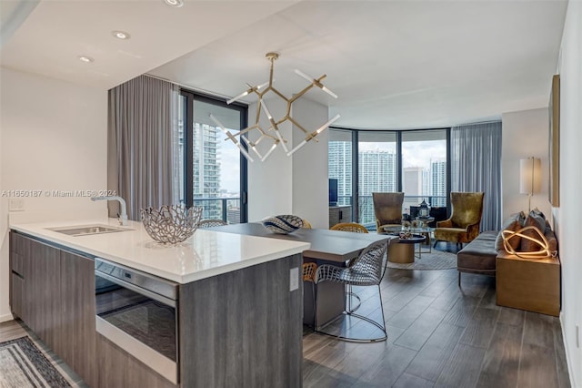 kitchen featuring kitchen peninsula, floor to ceiling windows, stainless steel oven, sink, and dark hardwood / wood-style floors