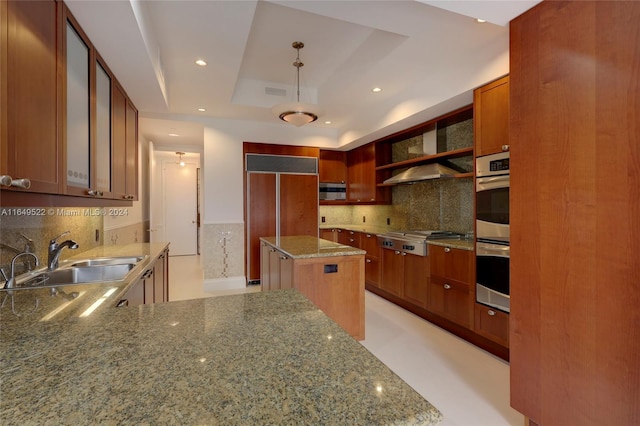 kitchen with light stone countertops, stainless steel appliances, a raised ceiling, and a sink