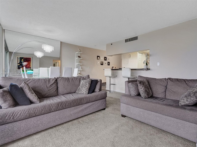 carpeted living room with a textured ceiling and a notable chandelier