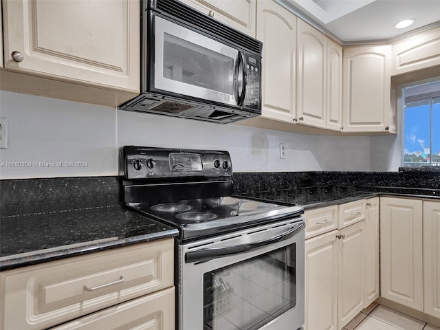 kitchen with light tile patterned floors, dark stone countertops, and electric range