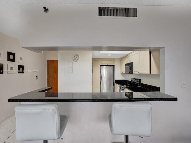 kitchen with appliances with stainless steel finishes, light tile patterned floors, a kitchen breakfast bar, and kitchen peninsula