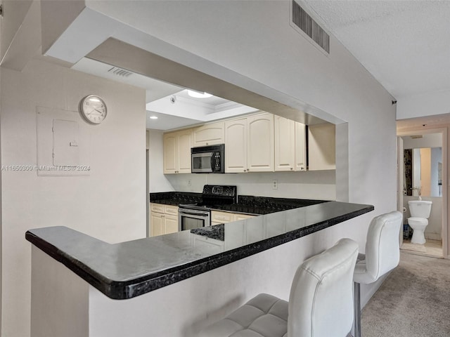 kitchen with a textured ceiling, a kitchen breakfast bar, stainless steel electric range oven, light carpet, and kitchen peninsula