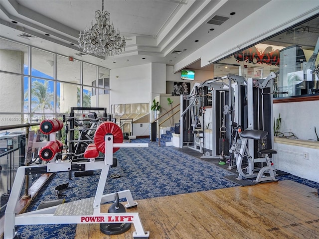 exercise room featuring a wall of windows, hardwood / wood-style floors, and a chandelier