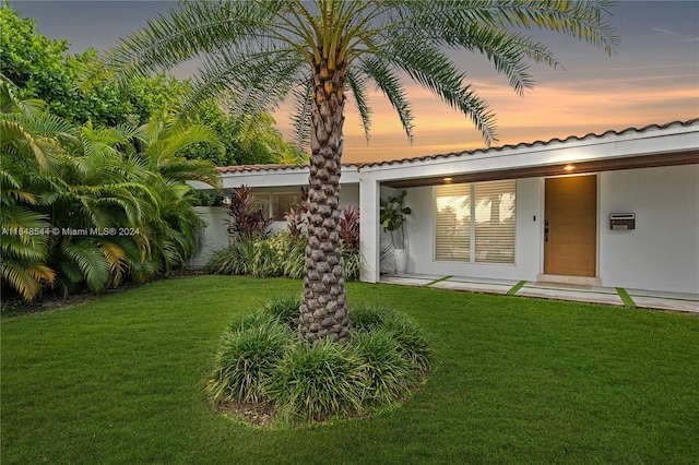 back house at dusk with a lawn