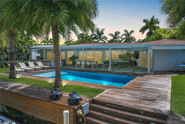 pool at dusk with an outdoor pool, outdoor lounge area, a ceiling fan, and a patio