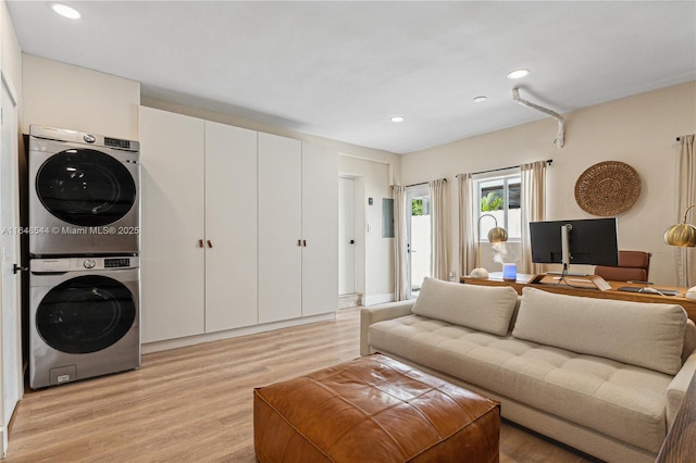 living room featuring light wood-style flooring, stacked washer / drying machine, and recessed lighting