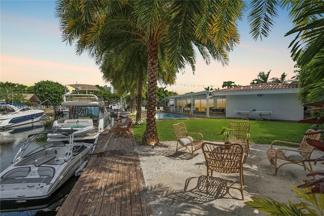 view of dock with a patio area, a yard, and a community pool