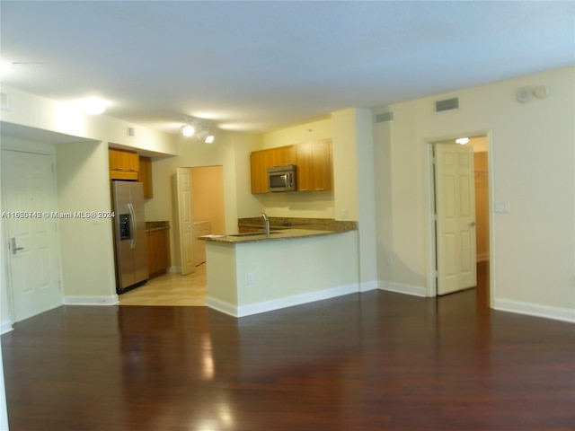 kitchen featuring stainless steel appliances, sink, kitchen peninsula, and hardwood / wood-style flooring