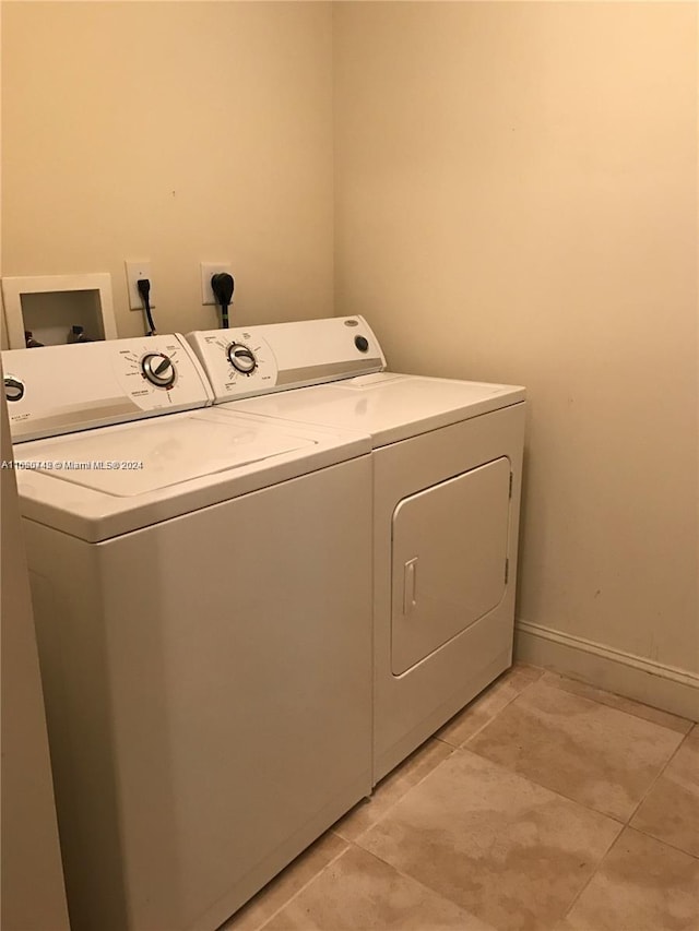 laundry area with light tile patterned floors and washing machine and dryer