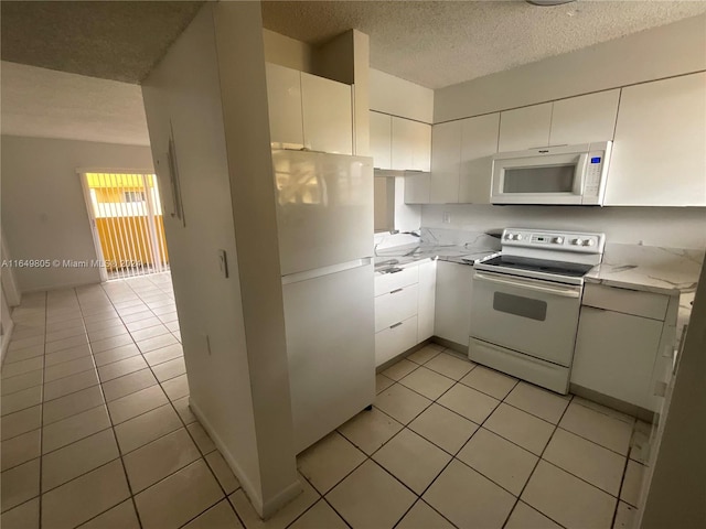 kitchen featuring white appliances, a textured ceiling, white cabinetry, and light tile patterned flooring