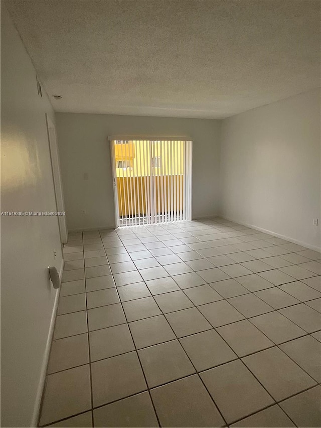 spare room with a textured ceiling and light tile patterned flooring