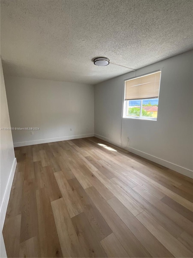 spare room featuring light hardwood / wood-style floors and a textured ceiling