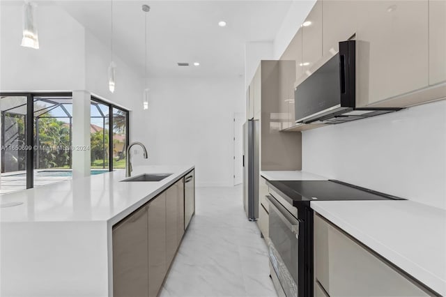 kitchen featuring appliances with stainless steel finishes, pendant lighting, a center island with sink, and sink