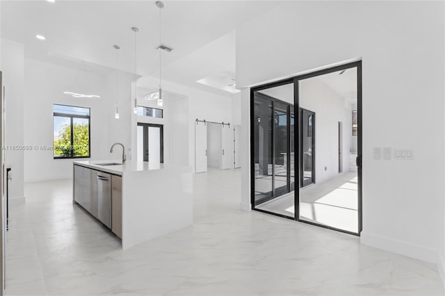 kitchen featuring pendant lighting, dishwasher, a center island with sink, and sink