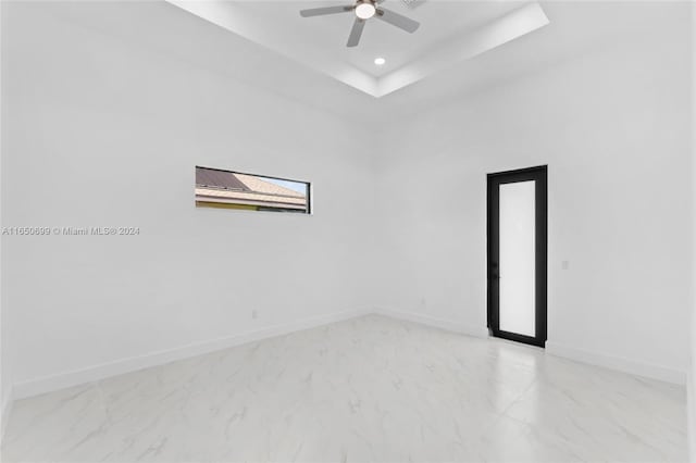 unfurnished room featuring ceiling fan and a raised ceiling