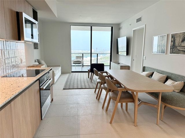 tiled dining space with a healthy amount of sunlight and expansive windows