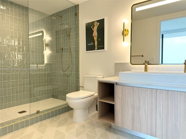 bathroom with tile patterned floors, toilet, a tile shower, and vanity