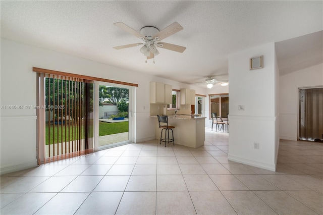 kitchen with cream cabinetry, a textured ceiling, a peninsula, and light tile patterned floors