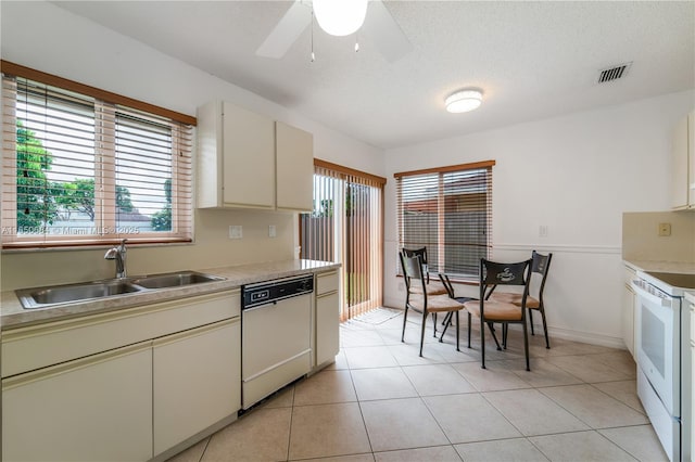 kitchen with light tile patterned floors, light countertops, a sink, a textured ceiling, and white appliances