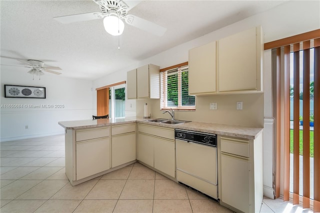 kitchen with a sink, white dishwasher, light countertops, and cream cabinetry