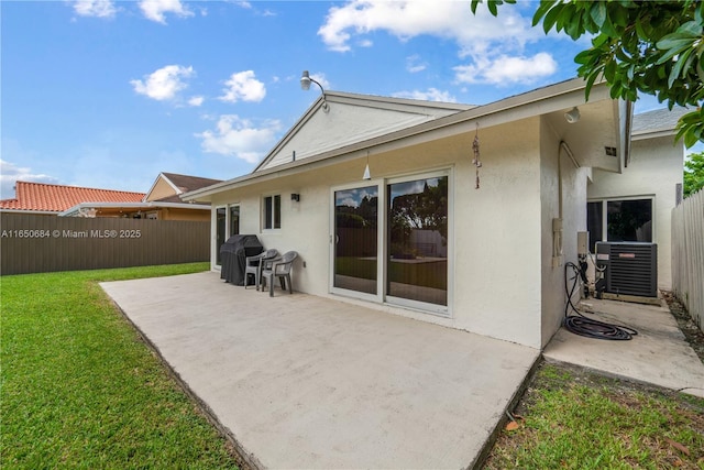 rear view of property with a yard, a patio, central AC, and stucco siding