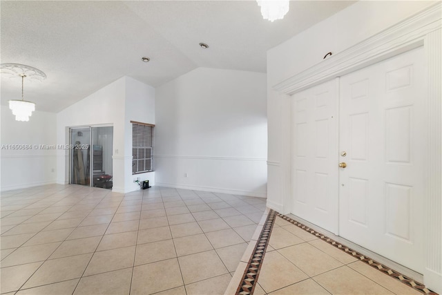 interior space featuring a chandelier, light tile patterned flooring, vaulted ceiling, and baseboards