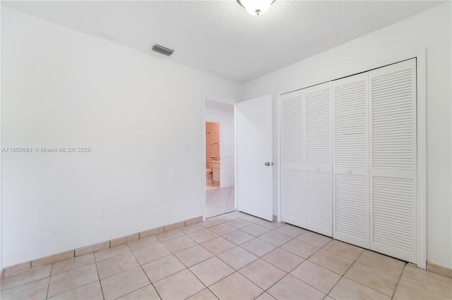 unfurnished bedroom with visible vents, a textured ceiling, and light tile patterned floors