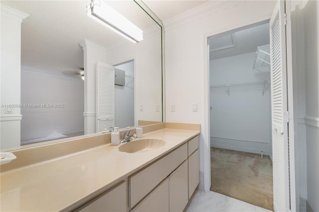 bathroom with tile patterned flooring, crown molding, vanity, and a textured ceiling