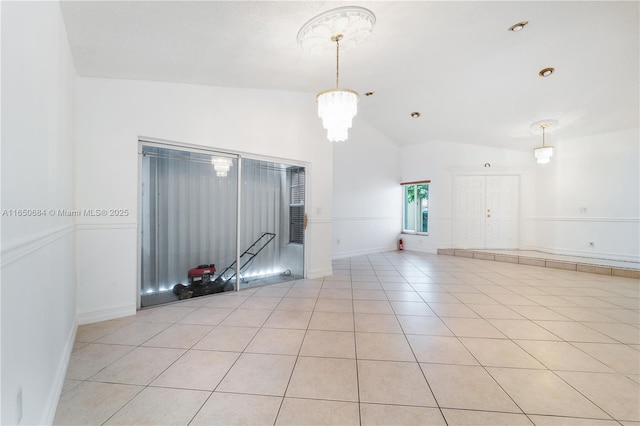 spare room featuring a chandelier, vaulted ceiling, baseboards, and light tile patterned floors