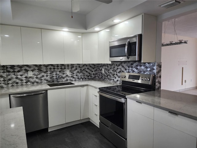 kitchen featuring light stone countertops, appliances with stainless steel finishes, sink, and white cabinetry