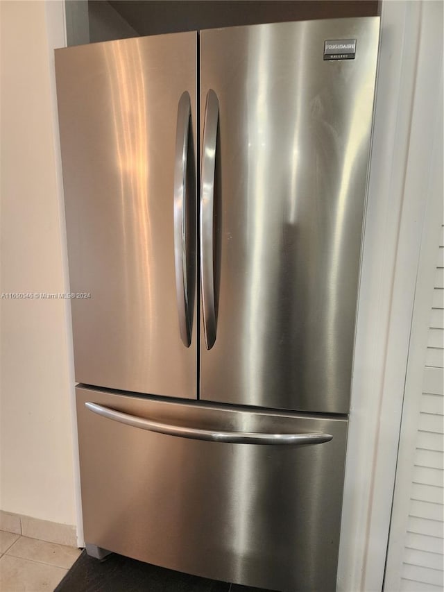 interior details with light tile patterned flooring and stainless steel fridge