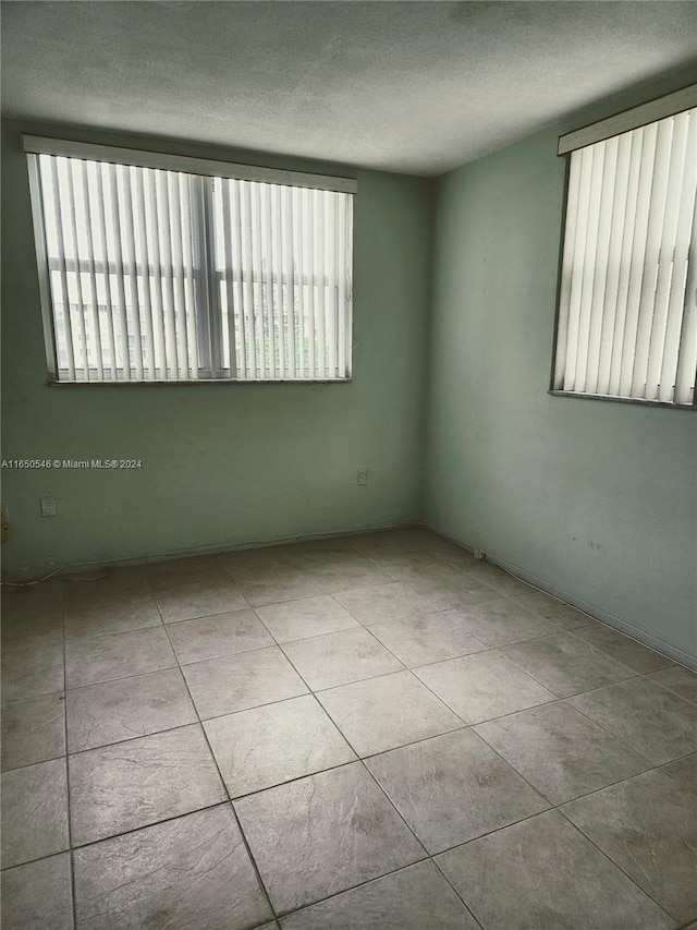 tiled empty room with a textured ceiling