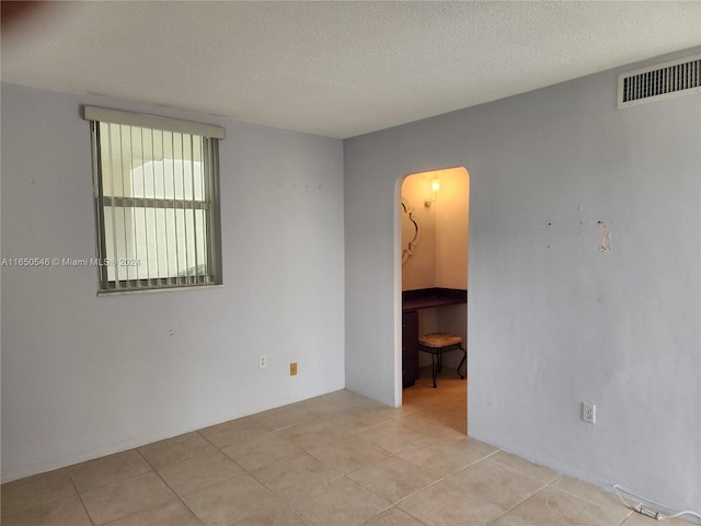 tiled empty room featuring a textured ceiling