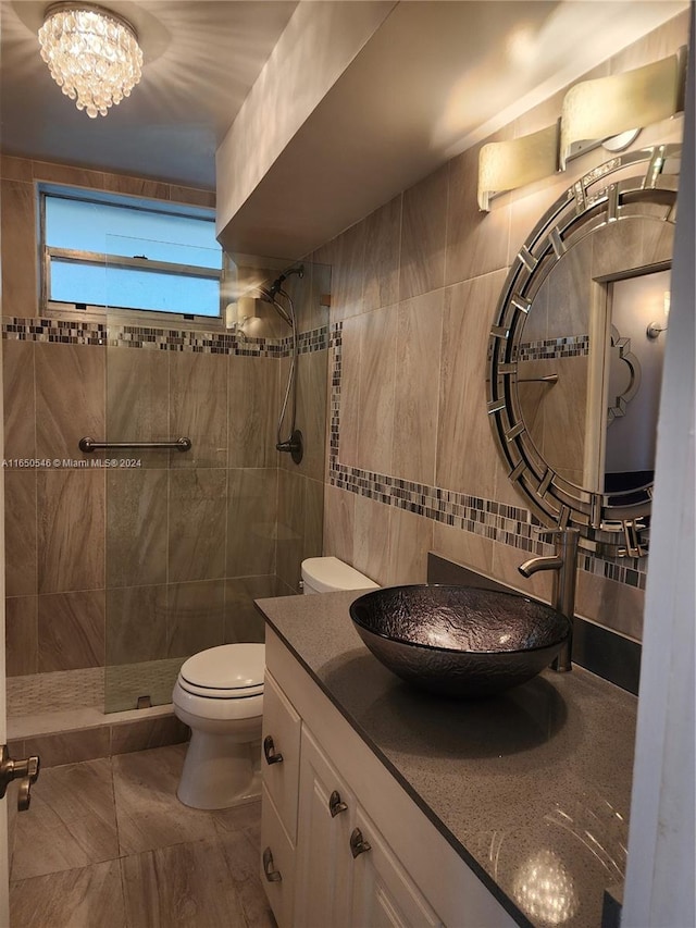 bathroom featuring tile walls, tiled shower, vanity, and toilet