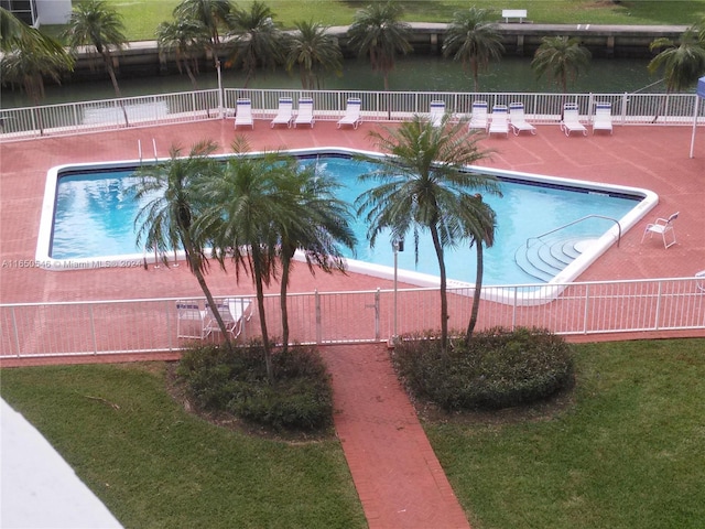 view of pool featuring a water view, a yard, and a patio area