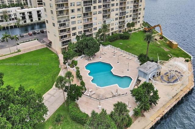 view of swimming pool featuring a water view, a yard, and a patio area