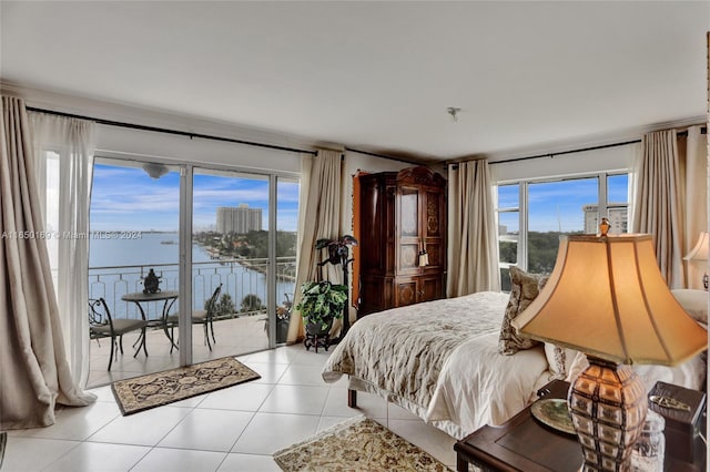 bedroom featuring access to exterior, light tile patterned floors, multiple windows, and a water view