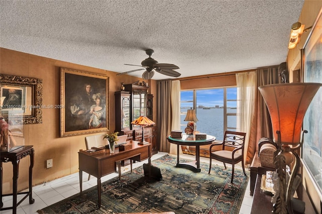 tiled office with a textured ceiling, a water view, and ceiling fan