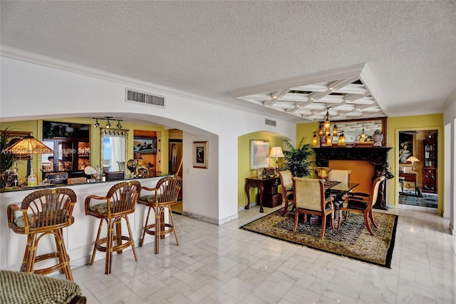 dining space with a textured ceiling, coffered ceiling, and bar area