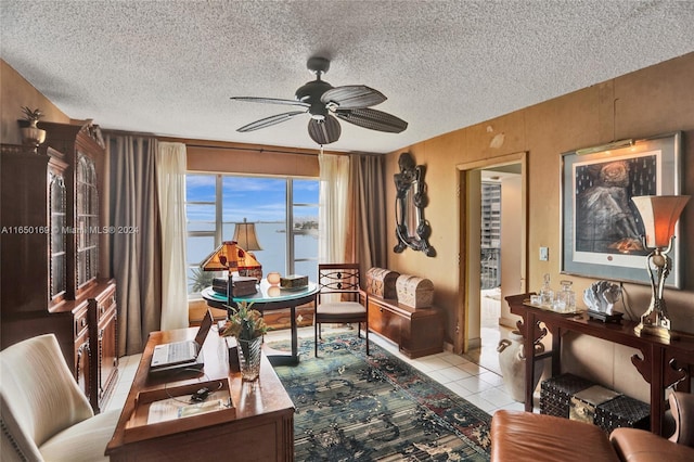 interior space featuring a water view, ceiling fan, light tile patterned floors, and a textured ceiling