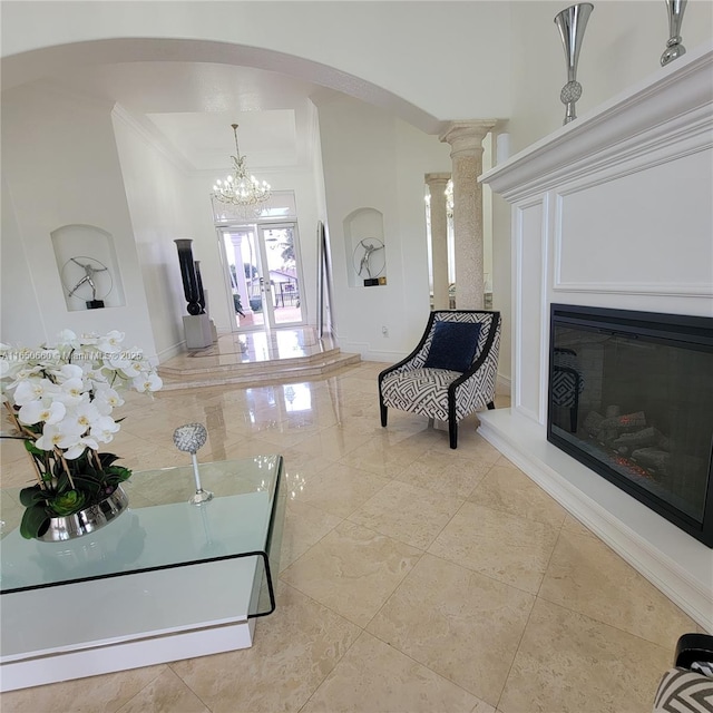 interior space with baseboards, arched walkways, a glass covered fireplace, a high ceiling, and crown molding